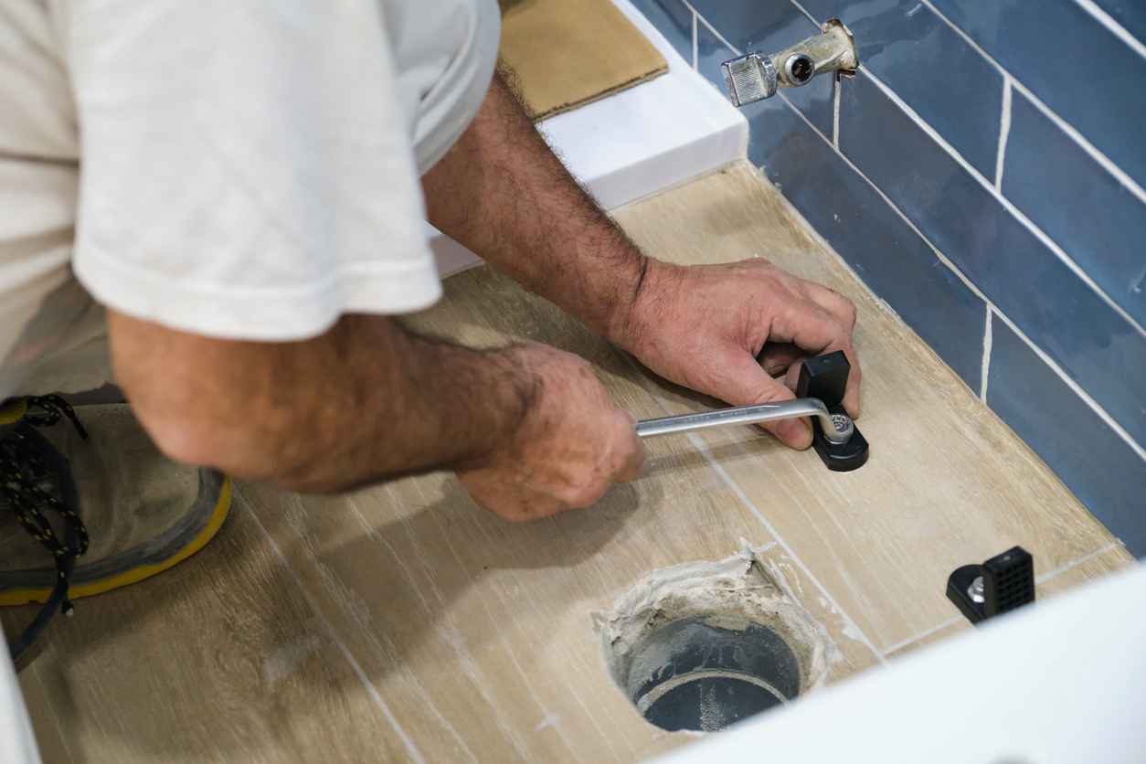 plumber installing toilet drain flange in a house