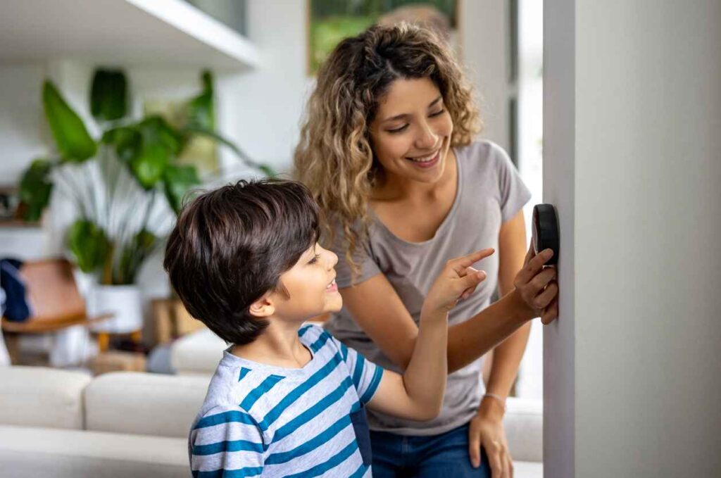 mother and son at home using a smart thermostat to adjust the temperature