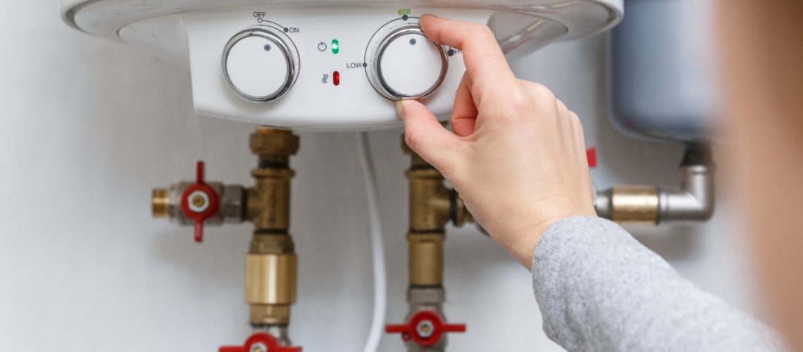 Female Hand Adjusting Tankless Water Heater